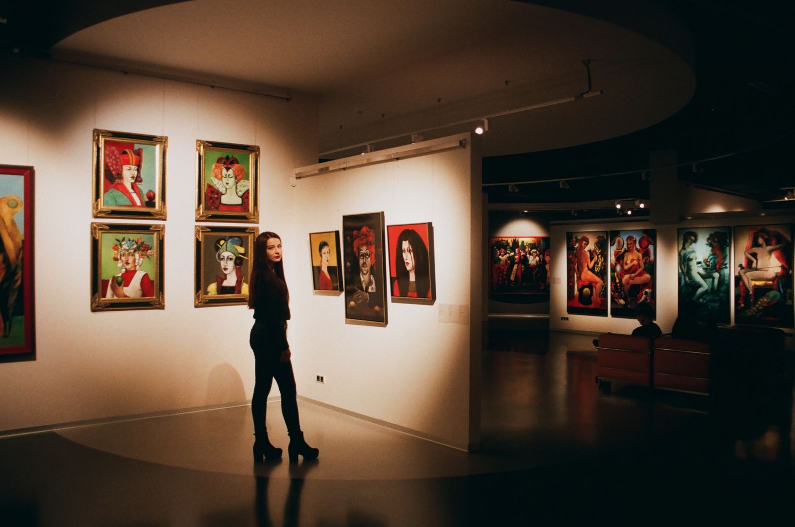 Visitor viewing framed portraits in a gallery, like the previews at Park West cruise ship art auctions