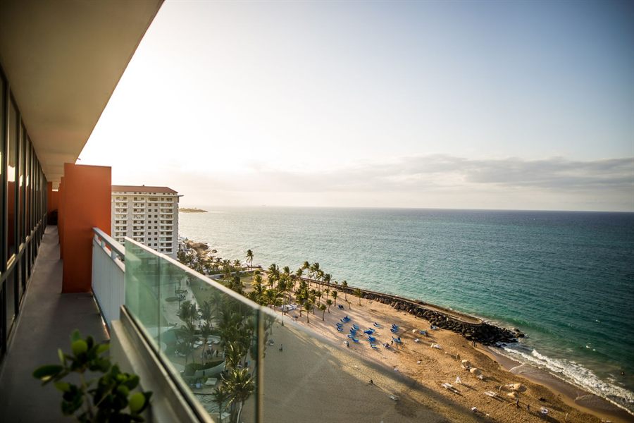 Private balcony with a glass rail overlooking the sea and a beach