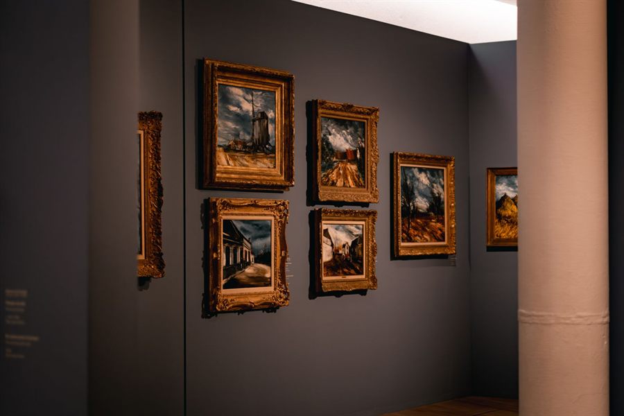 Framed paintings on a dark gallery wall