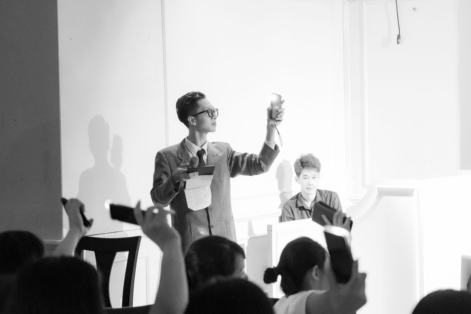 Auctioneer raising a hand to call bids before a seated audience, as at cruise auctions