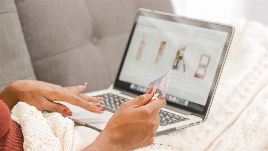 Hands holding a payment card in front of a laptop