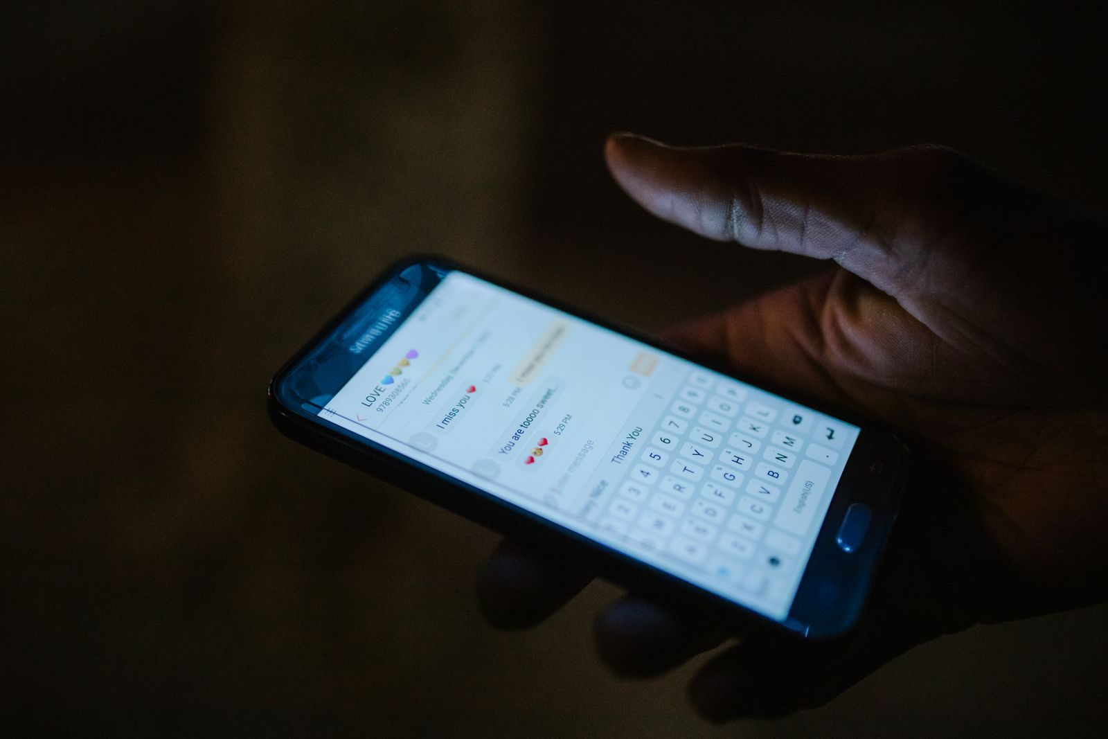 Hand holding a smartphone in a dark room