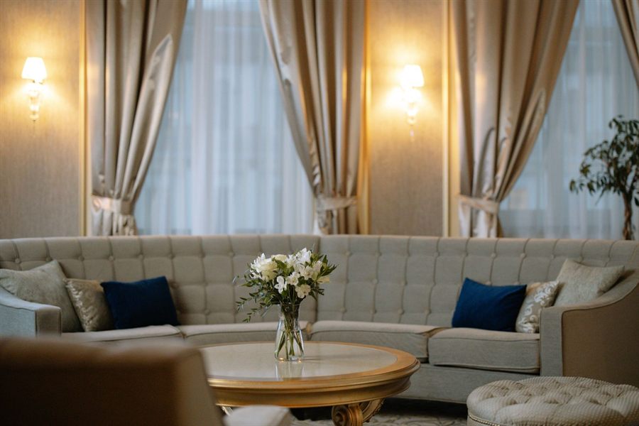 Elegant lounge with a curved sofa and tall curtained windows